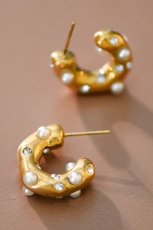 A pair of 18K gold dipped stainless steel hoop earrings with scattered pearls on a flat surface.