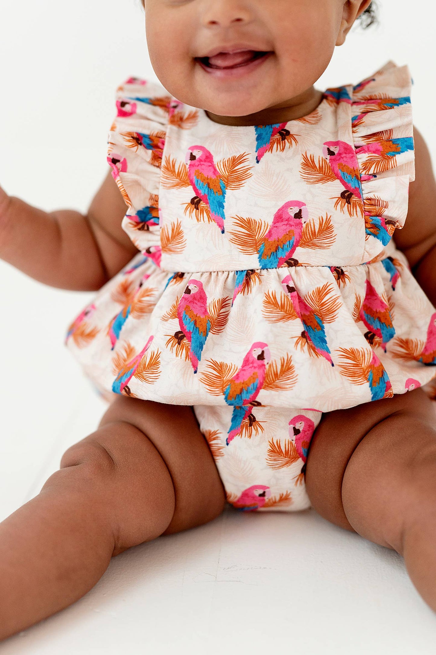 a baby sitting on the floor wearing a dress