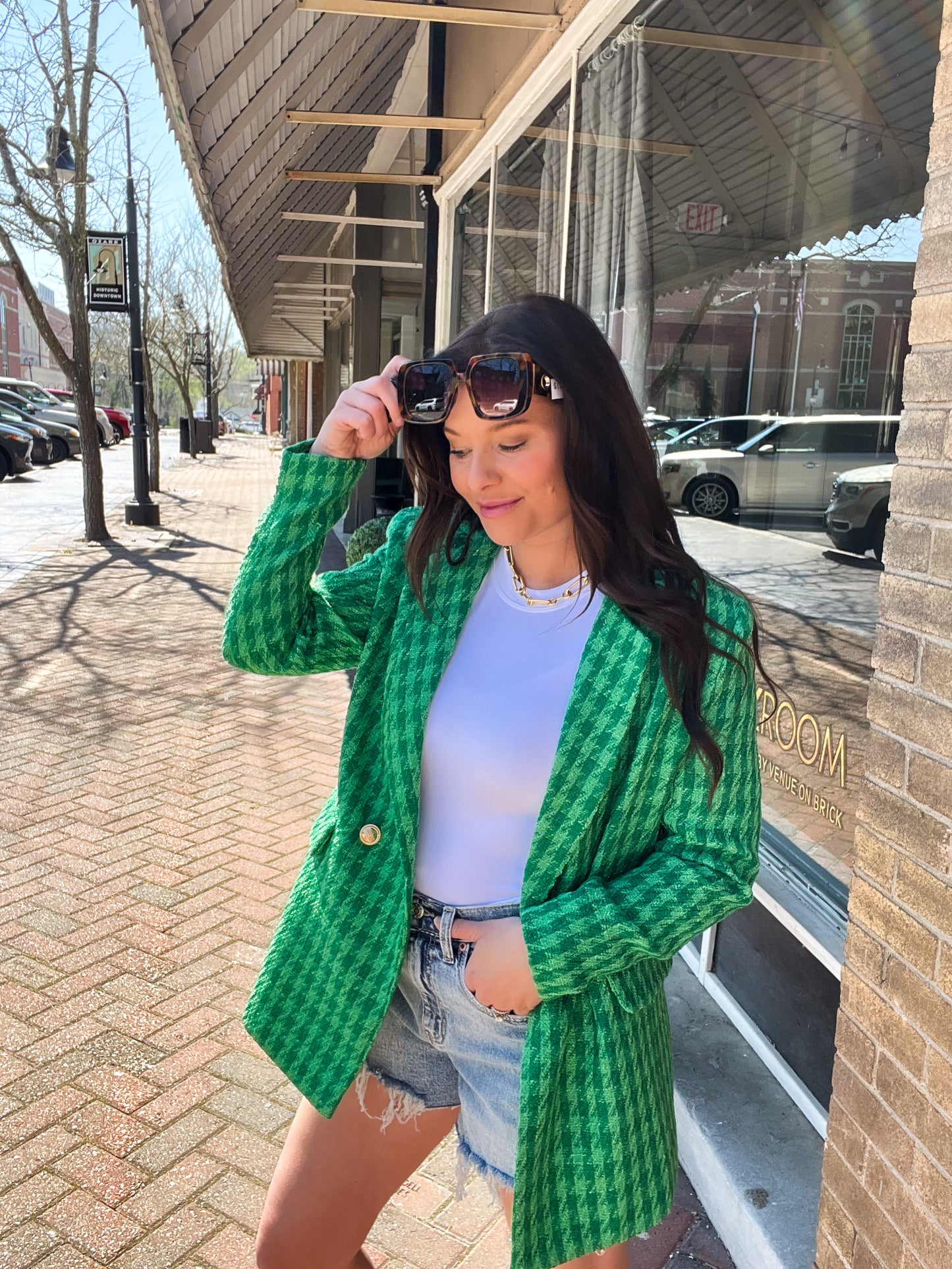 a woman standing on a sidewalk wearing a green cardigan