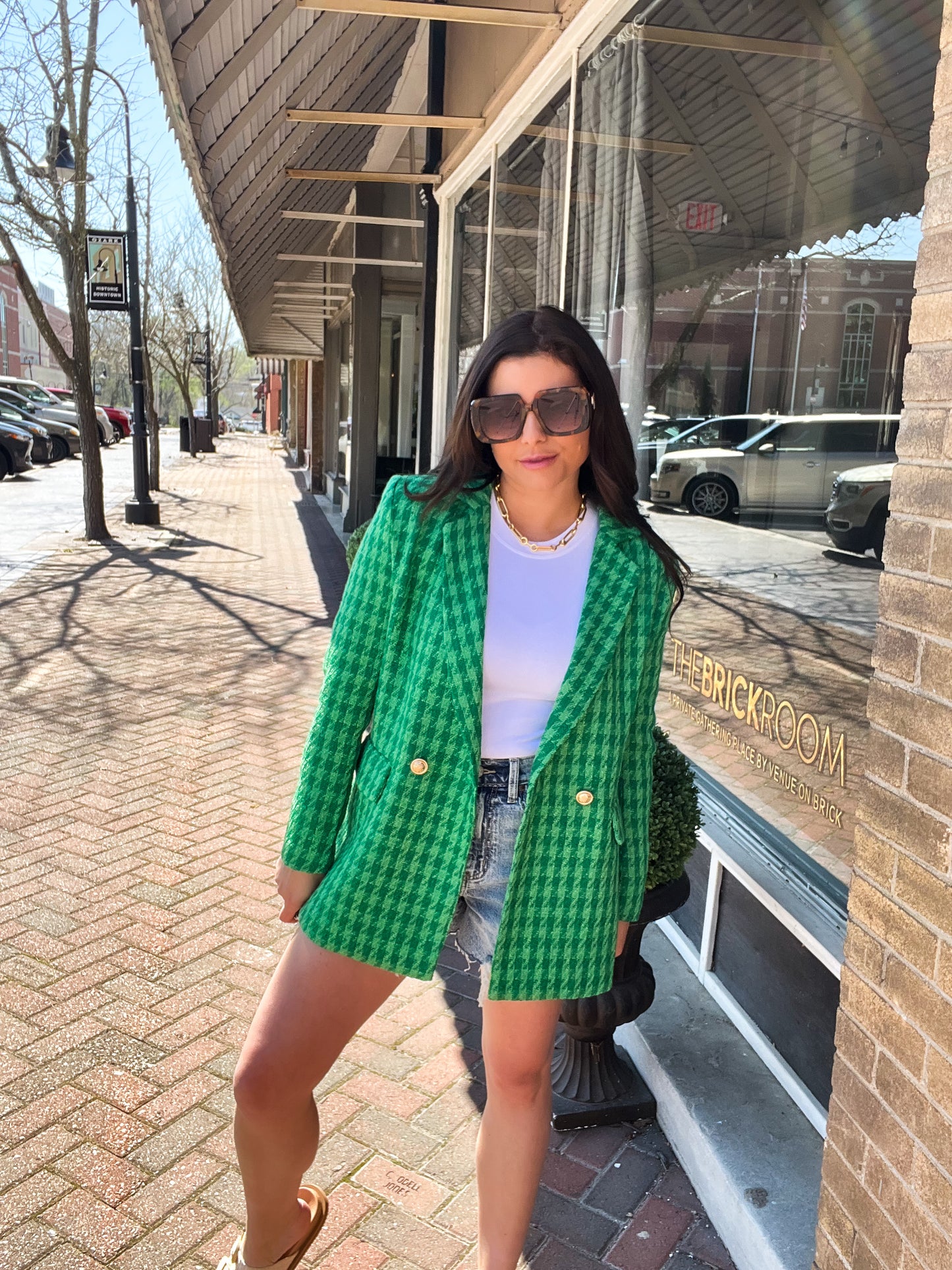 a woman standing on a sidewalk wearing a green jacket