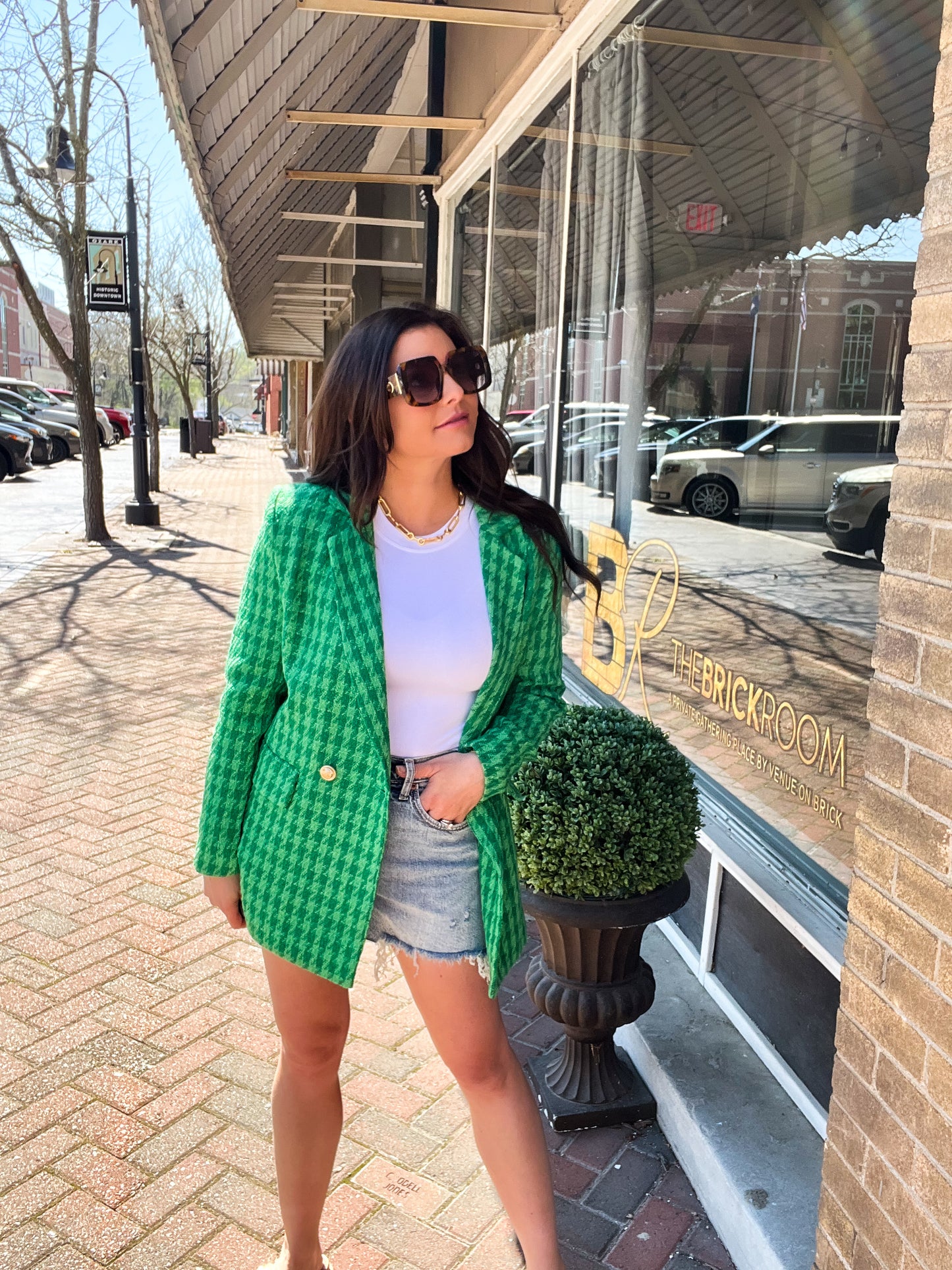 a woman in a green jacket is standing on a sidewalk