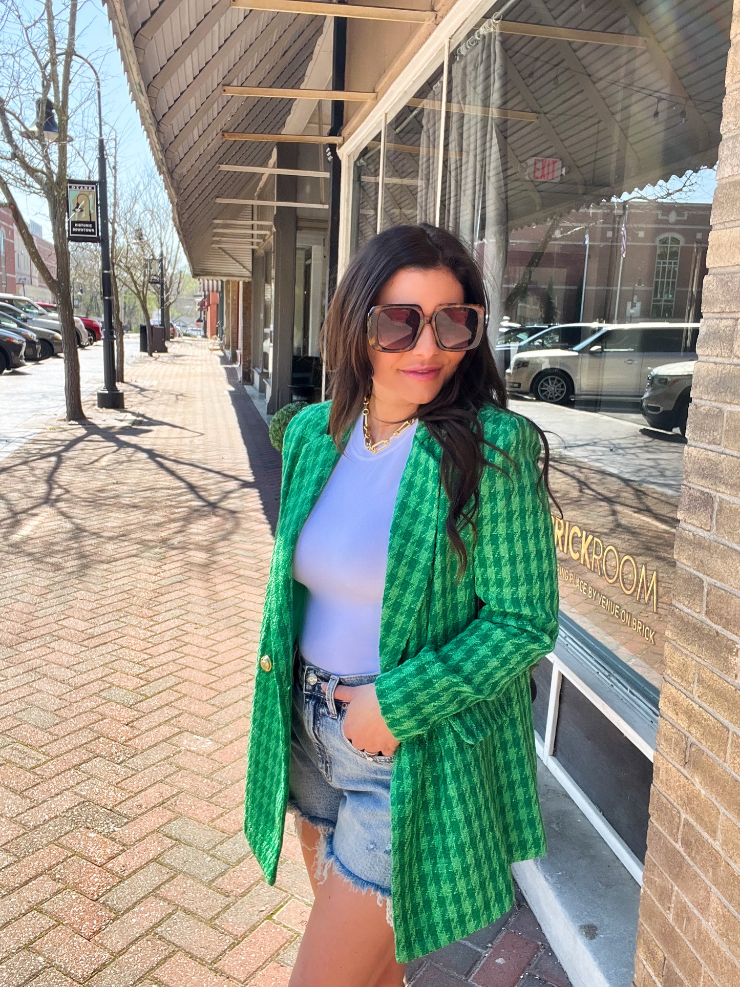 a woman standing on a sidewalk wearing a green jacket