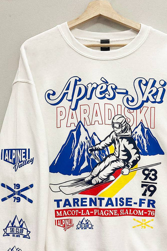 White sweatshirt with a graphic print of a skier and the text 'Apres Ski Paradiski', featuring mountainous terrain and the years '1979-89'.