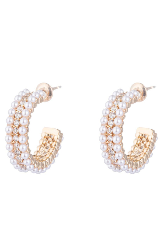 A pair of gold huggie hoop earrings with stacked glass pearl details, featuring CZ crystals, and a push-back closure.