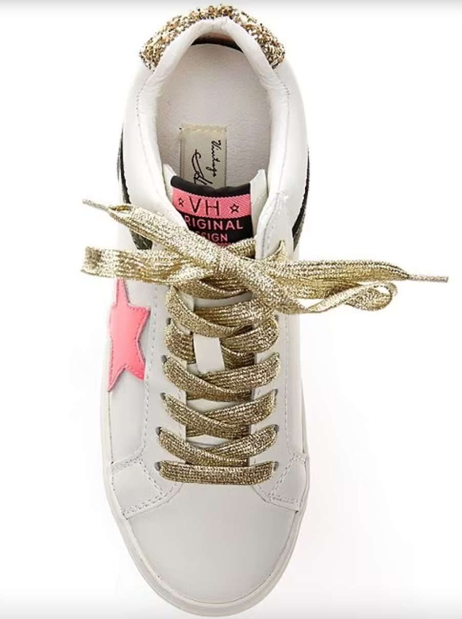 a white sneaker with a gold star on the side