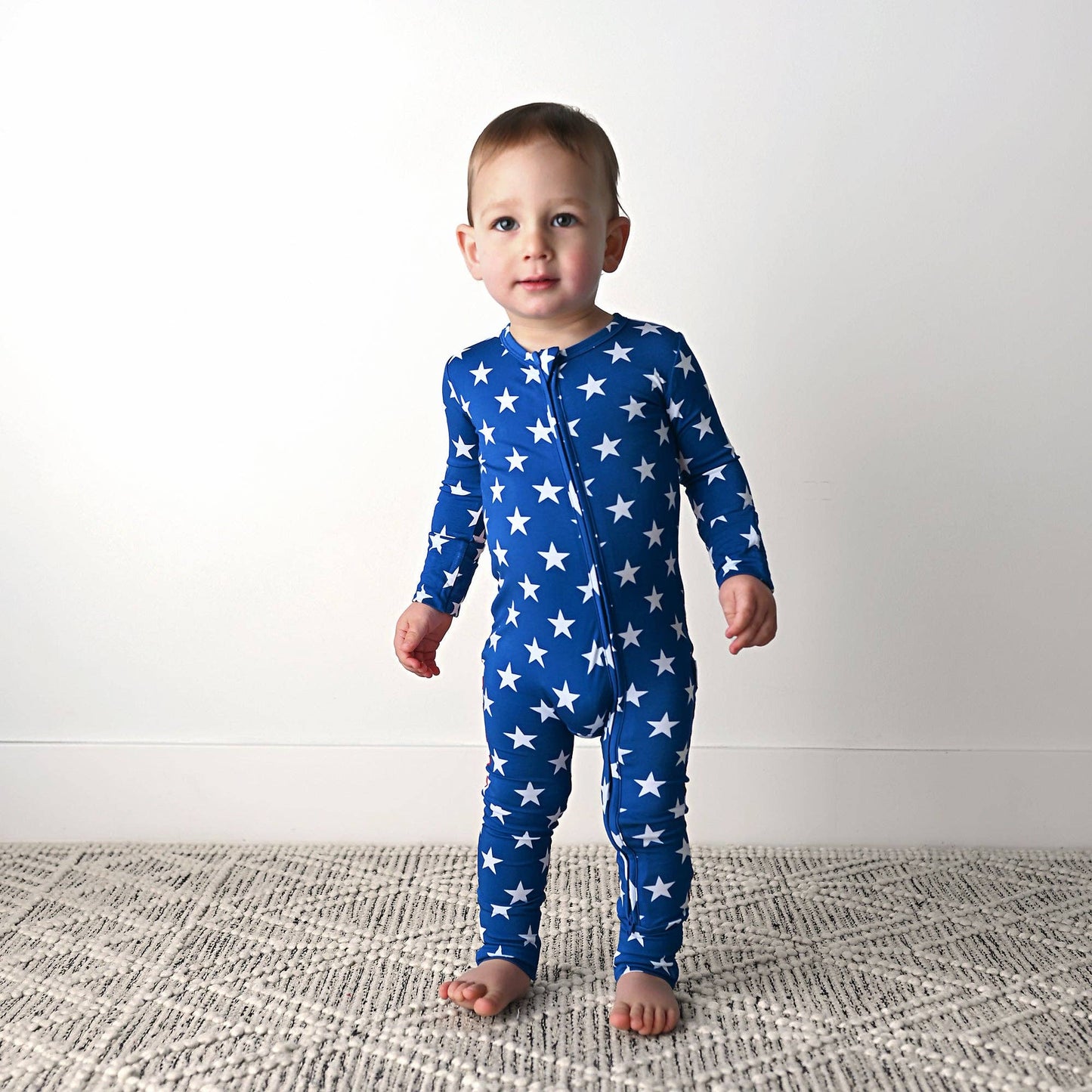 a little boy in a blue and white star print onesie