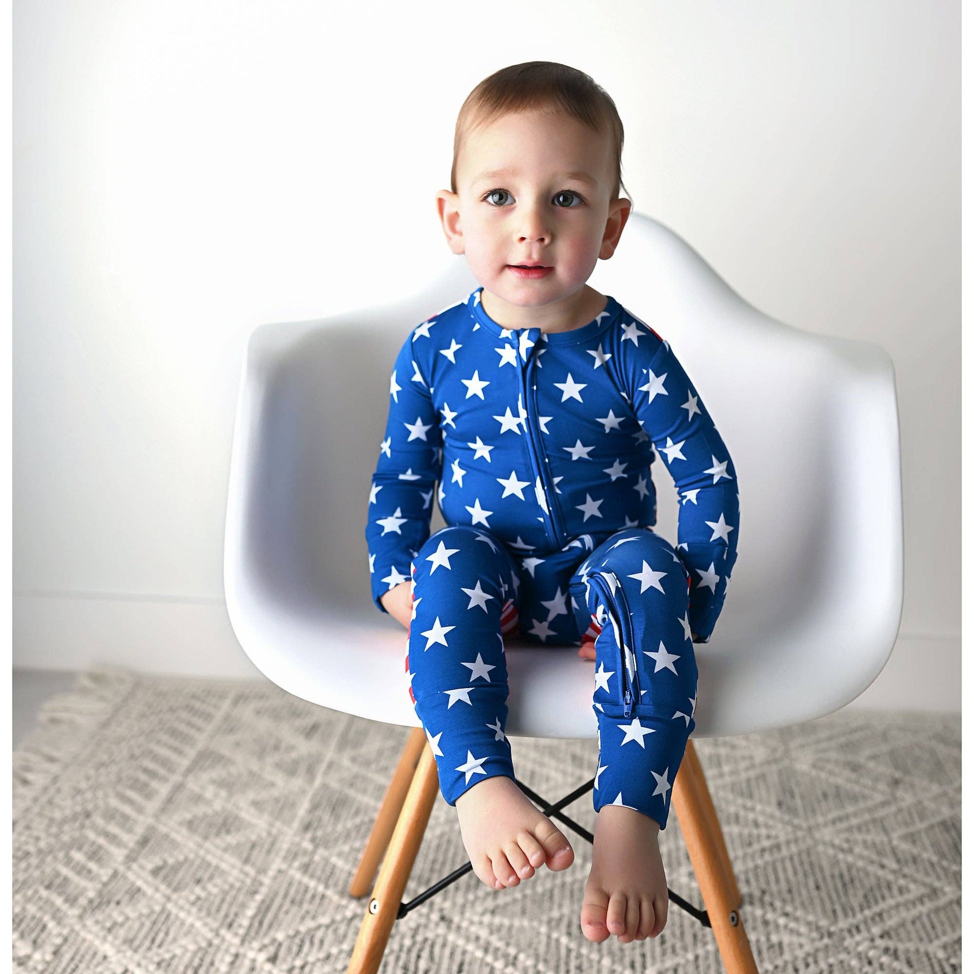 a baby sitting on a white chair wearing a blue and white star print pajamas