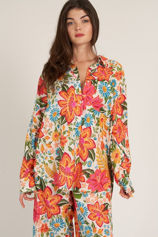 a woman is wearing a colorful floral shirt and pants