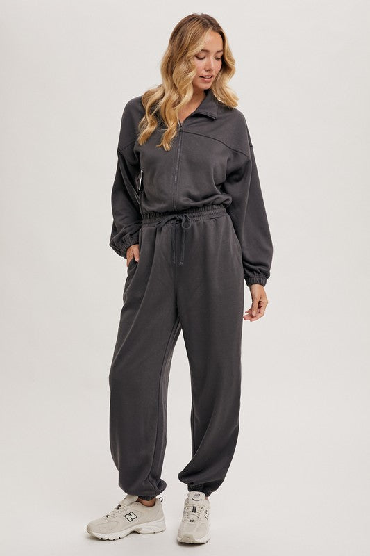 a woman wearing a black jumpsuit and sneakers