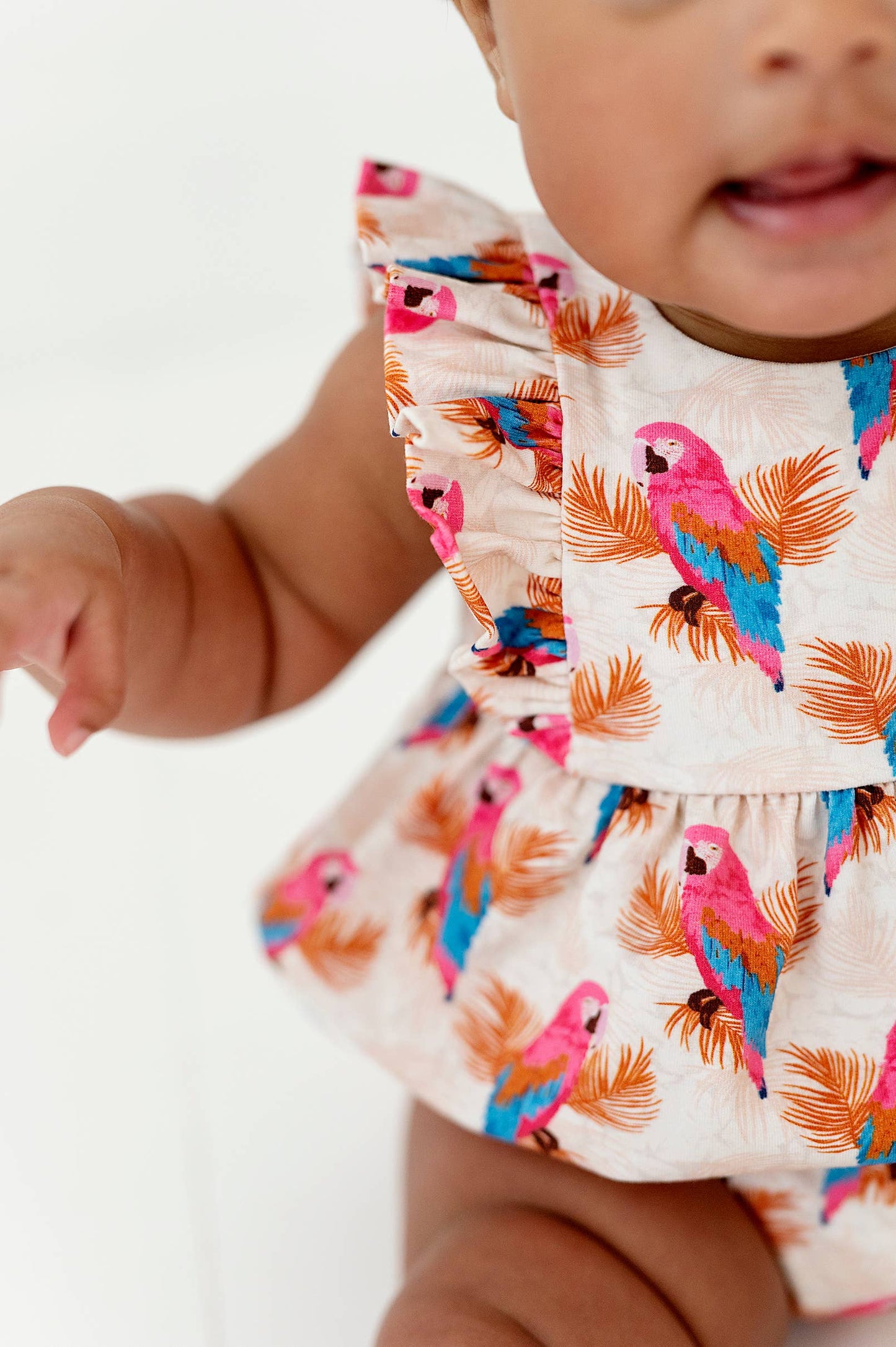 a baby girl wearing a pink and blue bird dress