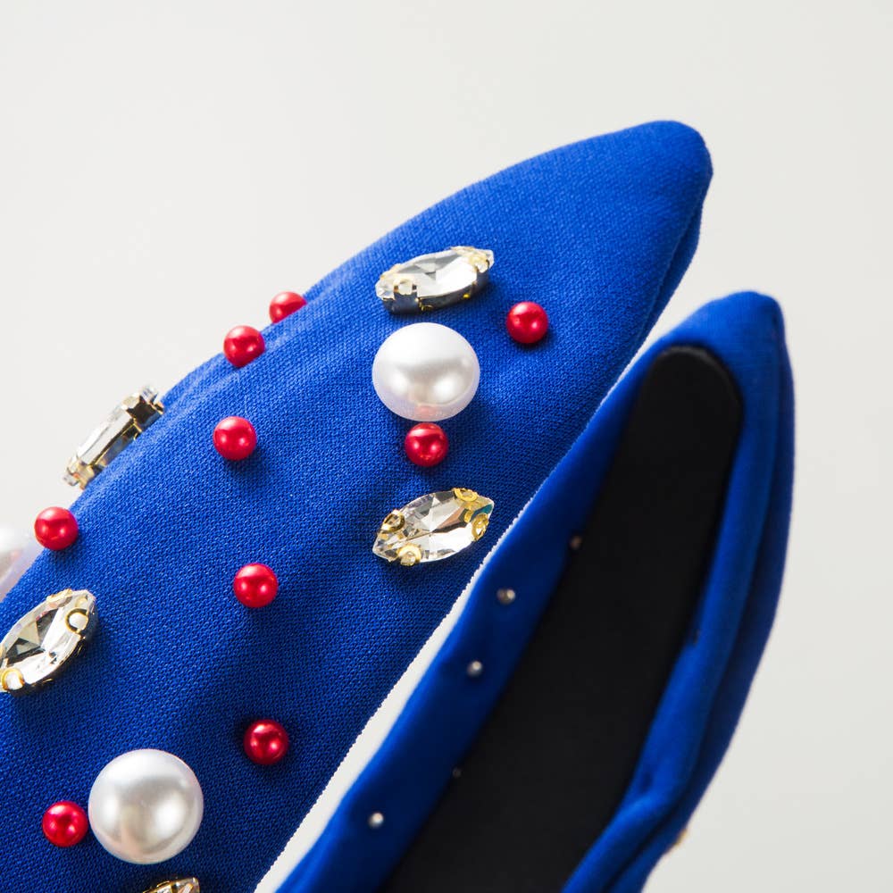 a blue purse with red and white pearls on it