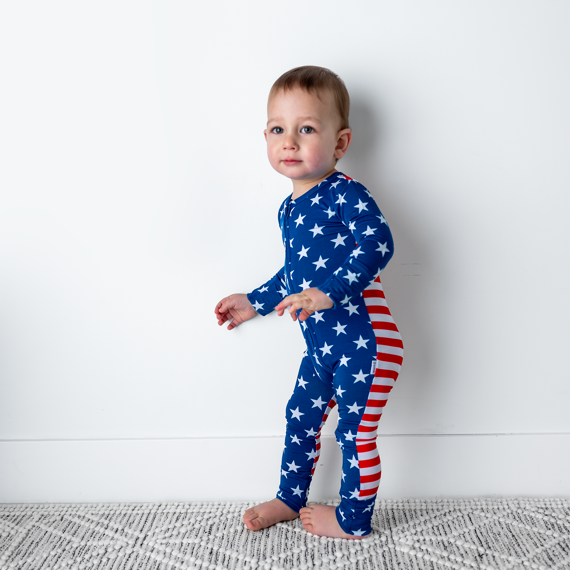 a little boy in a patriotic outfit standing in front of a wall