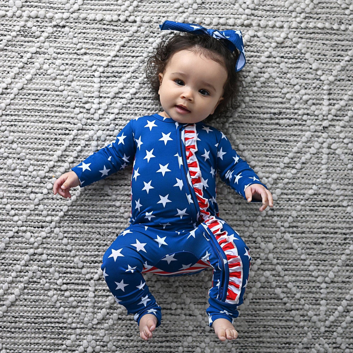 a baby laying on top of a blanket wearing a blue and red outfit