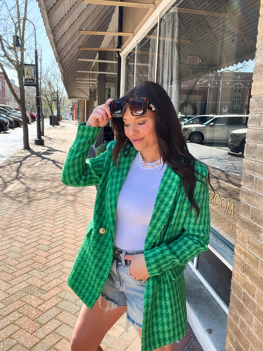 a woman standing on a sidewalk wearing a green cardigan