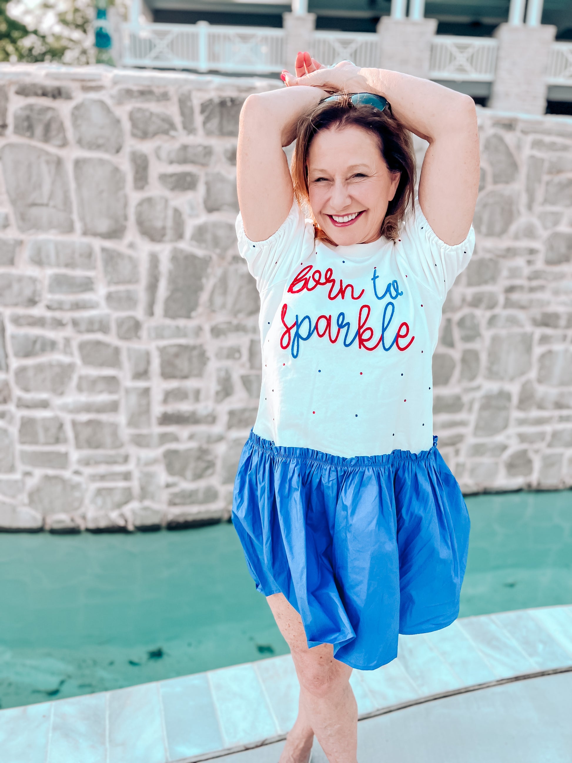 a woman standing in front of a pool with her hands on her head