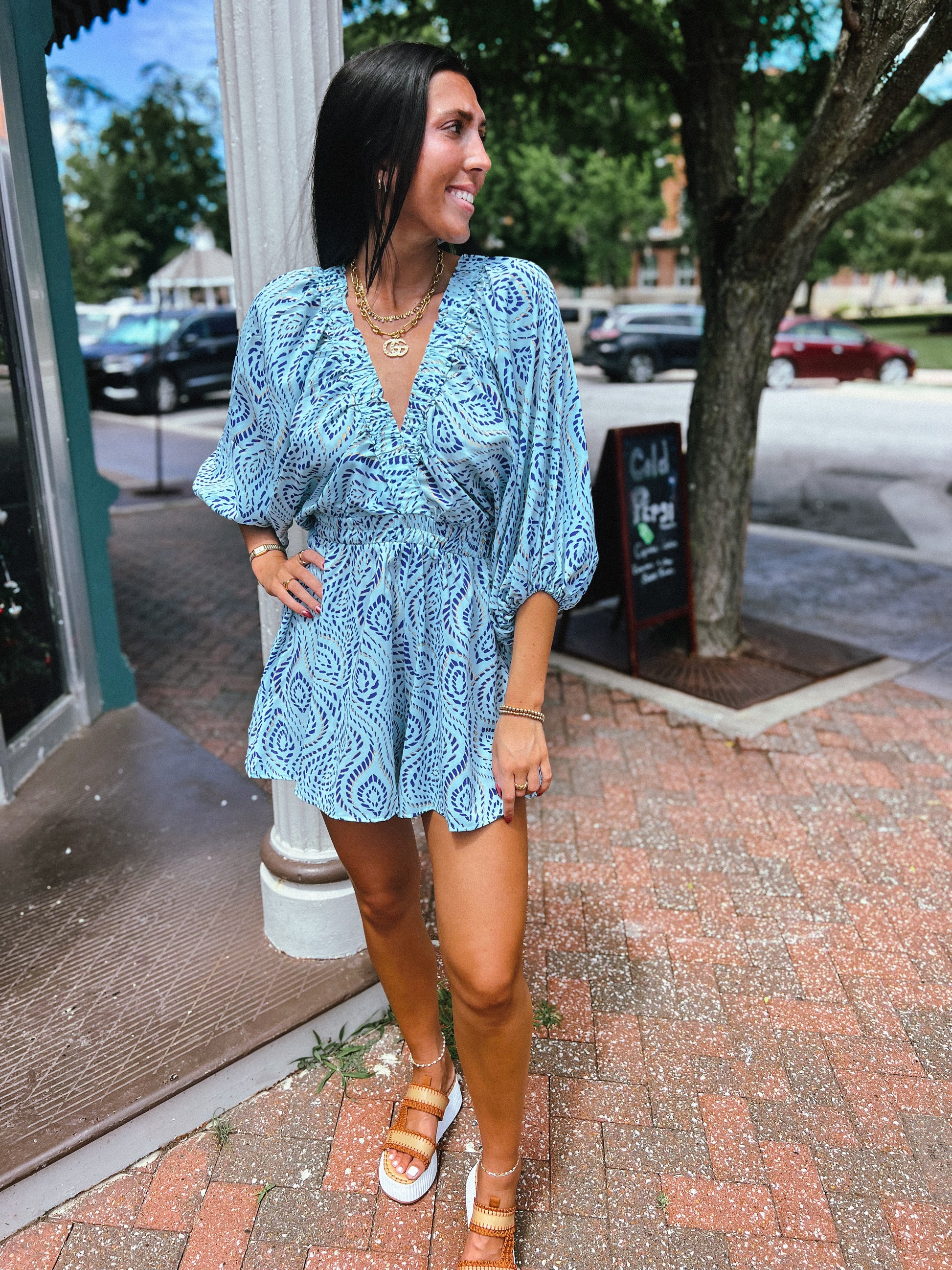 a woman in a blue dress standing on a sidewalk