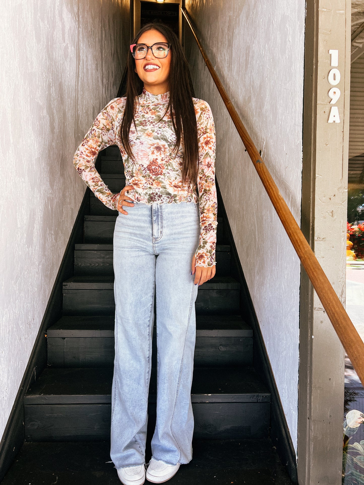 a woman standing at the bottom of a flight of stairs