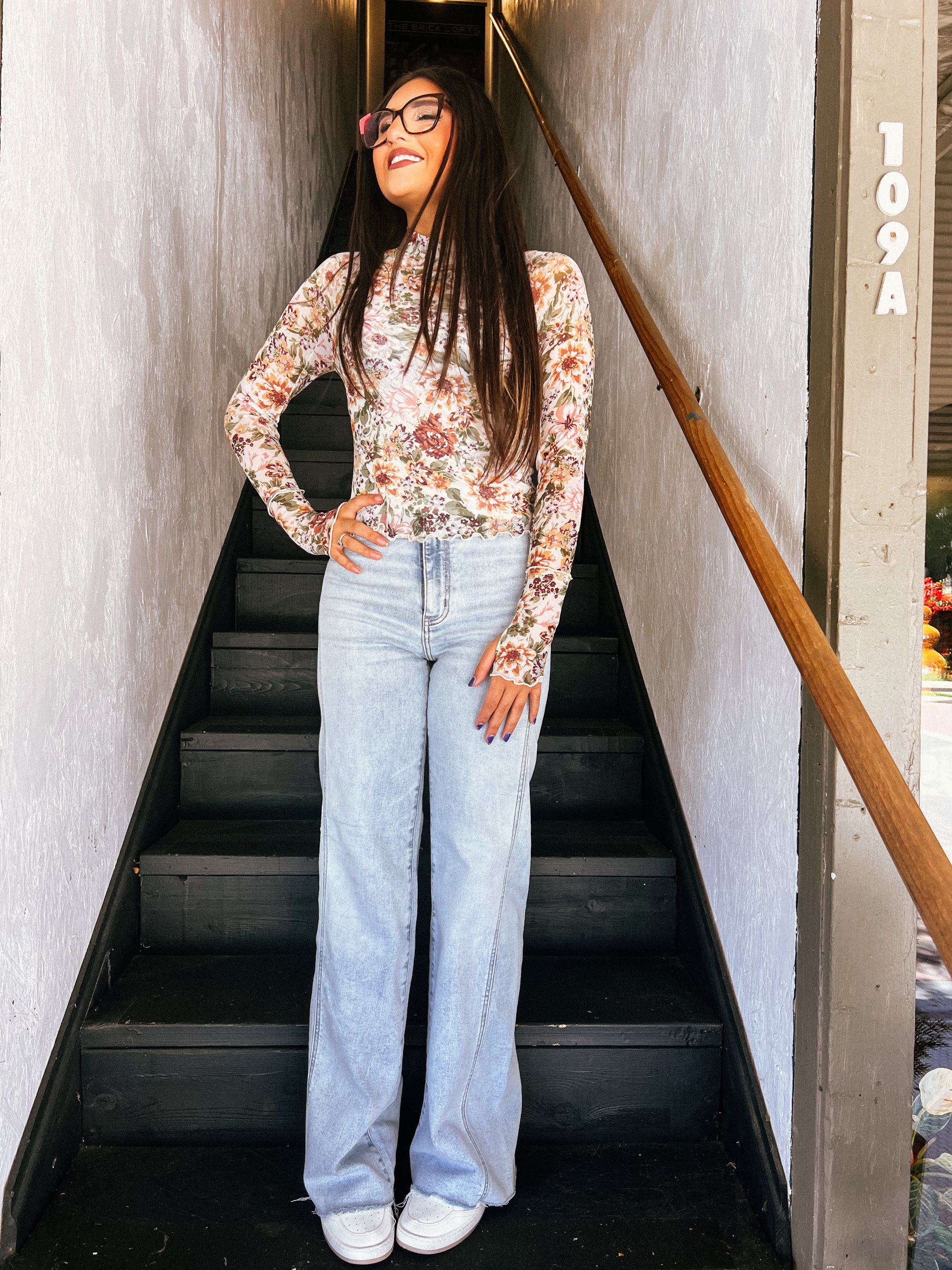 a woman standing at the bottom of a flight of stairs