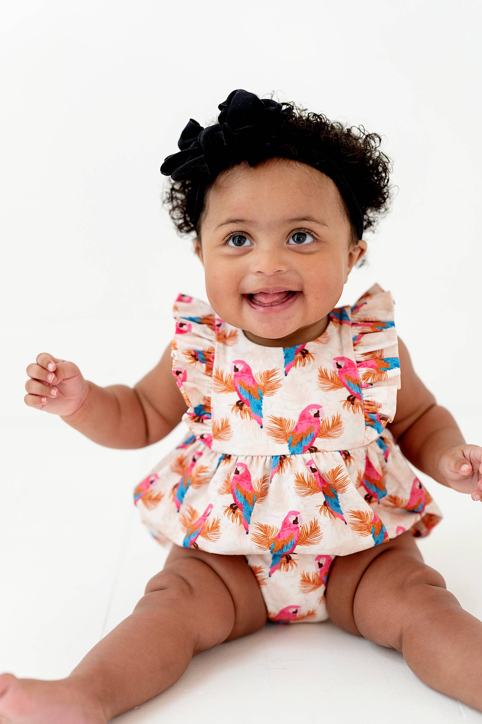 a baby girl sitting on the floor with a smile on her face