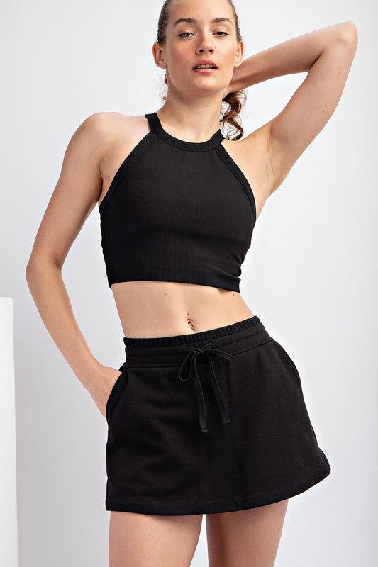 a woman wearing a black crop top and shorts